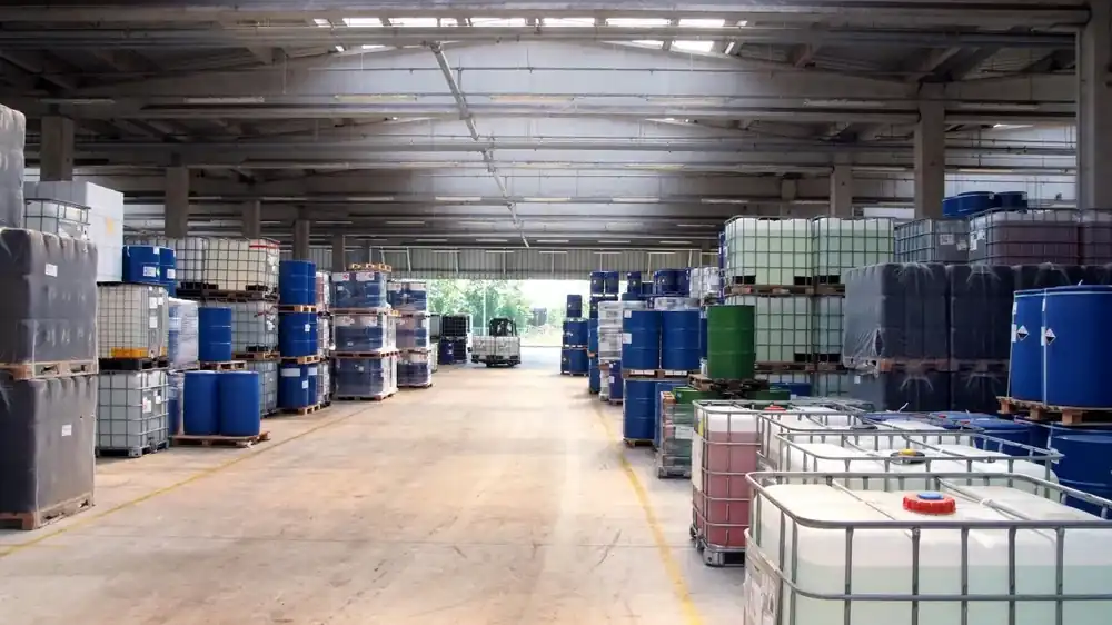 A wide, clear lane down the middle of a storage hall, marked with painted floor lines between pallet stacks