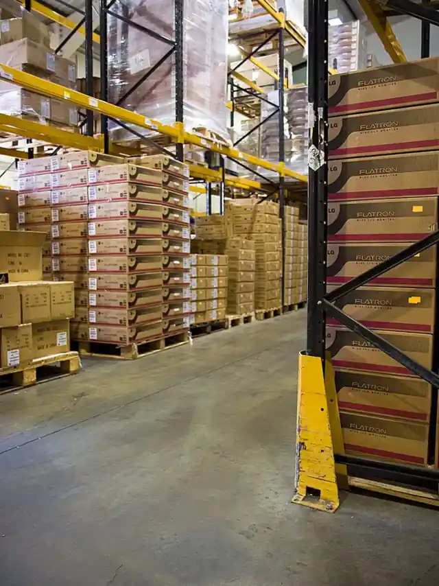 Looking down a racking aisle with cartons on each shelf level and a yellow guard at the end of the bay